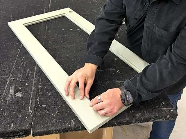Hender holder hjørnet på en lysegrønn rammefront på et arbeidsbord